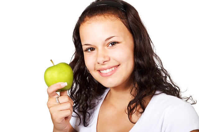 Dziewczyna trzyma w ręce zielone jabłko