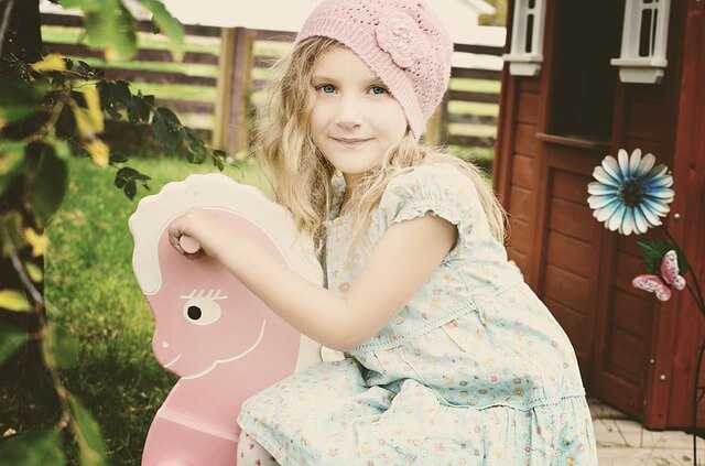 Dziewczynka na różowym koniku bujanym