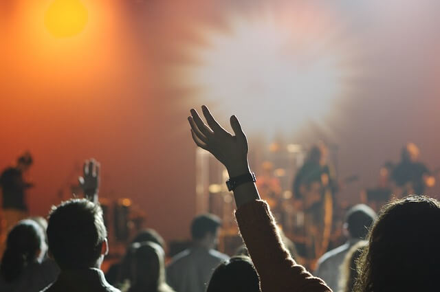 Ludzie z rękami uniesionymi podczas koncertu