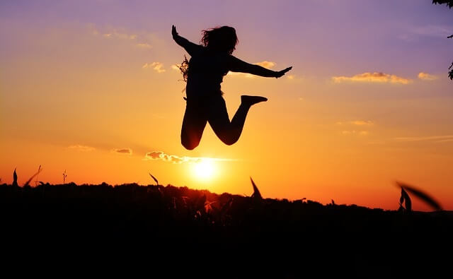 Sylwetka skaczącej kobiety na tle zachodzącego słońca