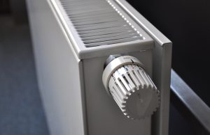Nowoczesny grzejnik ścienny z termostatem w jasnym wnętrzu.
